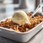 Apple crisp with oats baked until golden, served warm with ice cream.