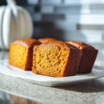 Mini pumpkin bread loaves with chocolate chips on a cooling rack, warm and moist with spiced aroma.