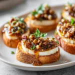 Close-up of pumpkin butter & brie crostini with pecan crunch, perfect Thanksgiving finger food.