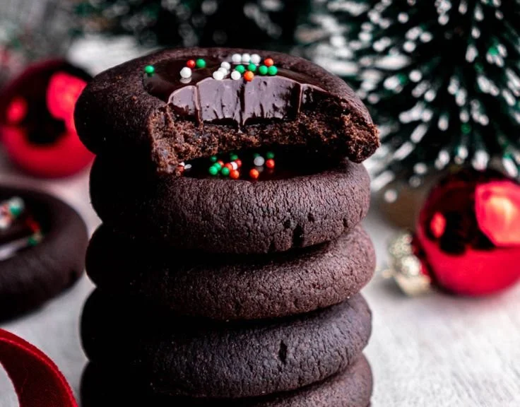Freshly baked Chocolate Thumbprint Cookies with jam filling on a parchment paper.
