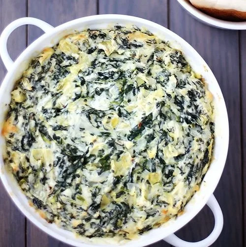 Bowl of creamy spinach artichoke dip served with tortilla chips.