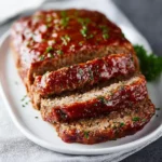 Delicious meatloaf on a plate with rich glaze and fresh herbs