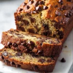 Sliced chocolate chip banana bread on a wooden cutting board