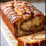 A slice of cinnamon swirl banana bread on a wooden cutting board.