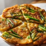 Crispy Korean spring onion pancake served on a plate with dipping sauce