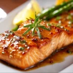 Maple Dijon Baked Salmon garnished with herbs on a platter.