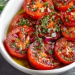 Delicious marinated tomatoes in a bowl, showcasing vibrant colors and herbs.