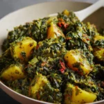 Bowl of creamy Spinach and Potato Curry garnished with spices and herbs