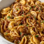 Vegan caramelized onion pasta served in a bowl with fresh herbs and spices