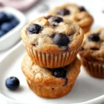 Blueberry Banana Muffins 2 Delicious Blueberry Banana Muffins ready to be served on a plate.