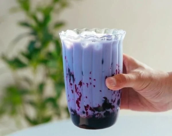 A delicious cup of blueberry boba milk tea with vibrant blueberry pearls.
