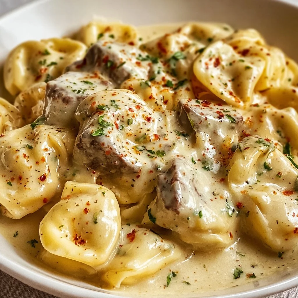 Cheesesteak tortellini in creamy provolone sauce garnished with herbs