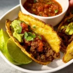 Crispy ground beef tacos loaded with toppings and served on a plate.