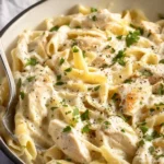 Creamy crockpot Chicken Alfredo dish served with pasta and parsley garnish