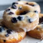Freshly baked blueberry donuts topped with icing and blueberries