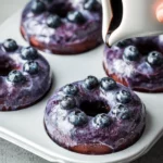 Homemade blueberry cake donuts topped with icing and fresh blueberries