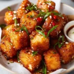 Plate of crispy sticky tofu garnished with herbs and spices