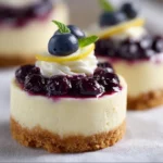 Mini lemon blueberry cheesecakes displayed on a plate, garnished with fresh blueberries.