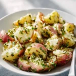 Bowl of Classic Italian Potato Salad garnished with fresh herbs