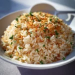 A bowl of Garlic Parmesan Rice garnished with parsley and cheese.