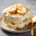 Bowl of old-fashioned homemade banana pudding topped with fresh bananas and whipped cream.