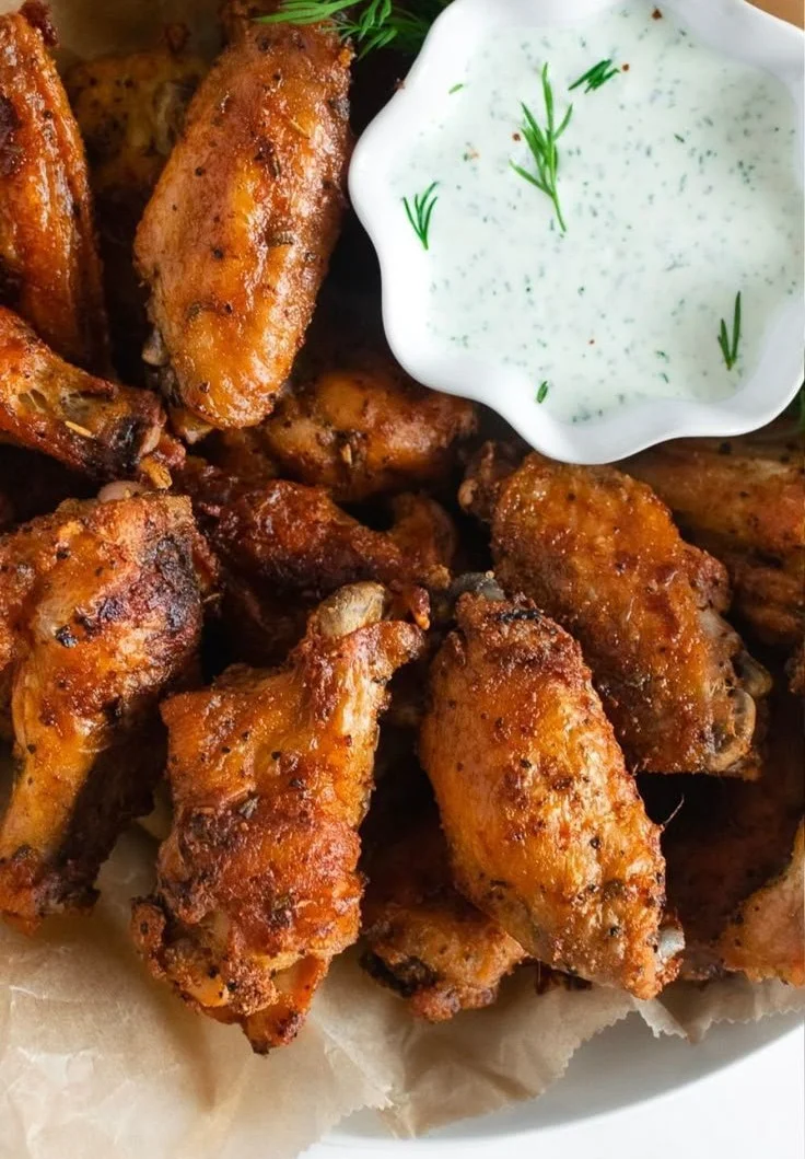 Plate of crispy baked chicken wings garnished with fresh herbs.