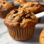 Flourless Peanut Butter Banana Muffins 3 Flourless peanut butter banana muffins on a wooden table.