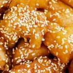Plate of homemade Honey Sesame Chicken garnished with sesame seeds and green onions