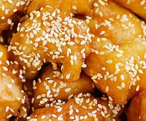 Plate of homemade Honey Sesame Chicken garnished with sesame seeds and green onions