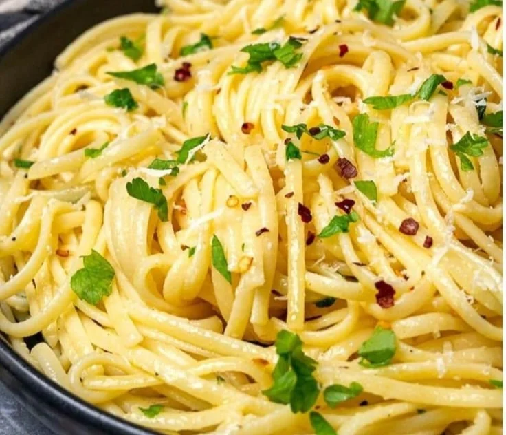 Plate of pasta topped with lemon butter garlic sauce and herbs.