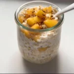Bowl of Peach Cobbler Overnight Oats topped with fresh peaches and cinnamon