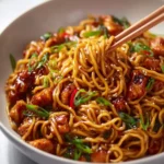 Plate of sticky garlic chicken noodles garnished with green onions