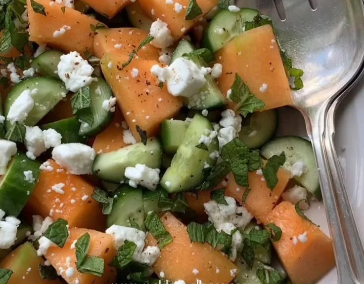 Cantaloupe melon salad with cucumber and feta cheese topped with fresh herbs.