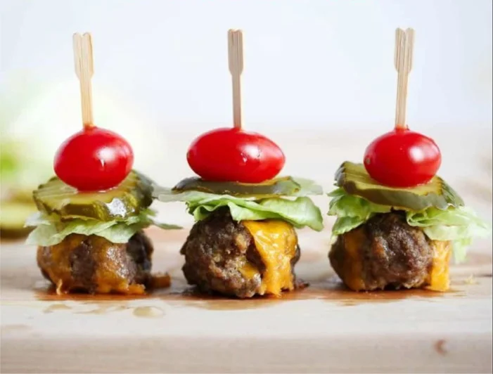 Delicious cheeseburger meatballs served with ketchup and pickles