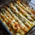 Cheesy Roasted Asparagus 3 Cheesy roasted asparagus topped with melted cheese and herbs on a baking tray