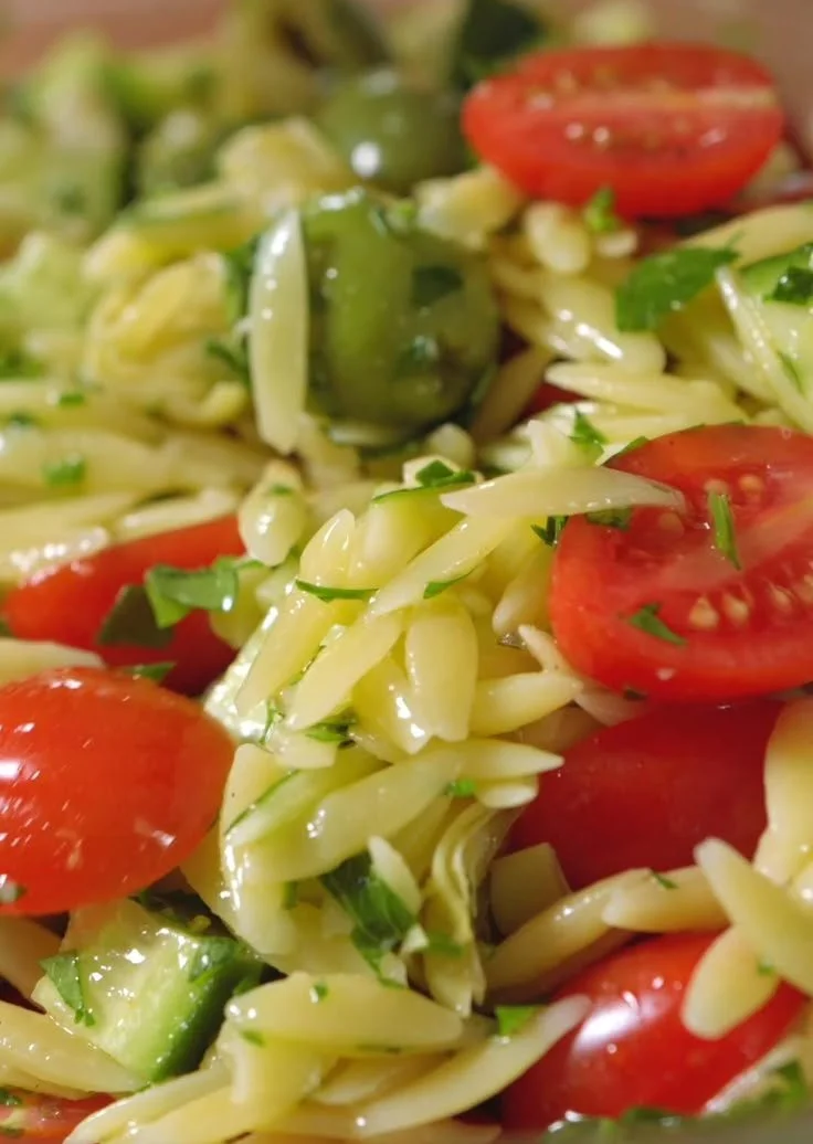 A colorful bowl of easy orzo salad with fresh vegetables and herbs