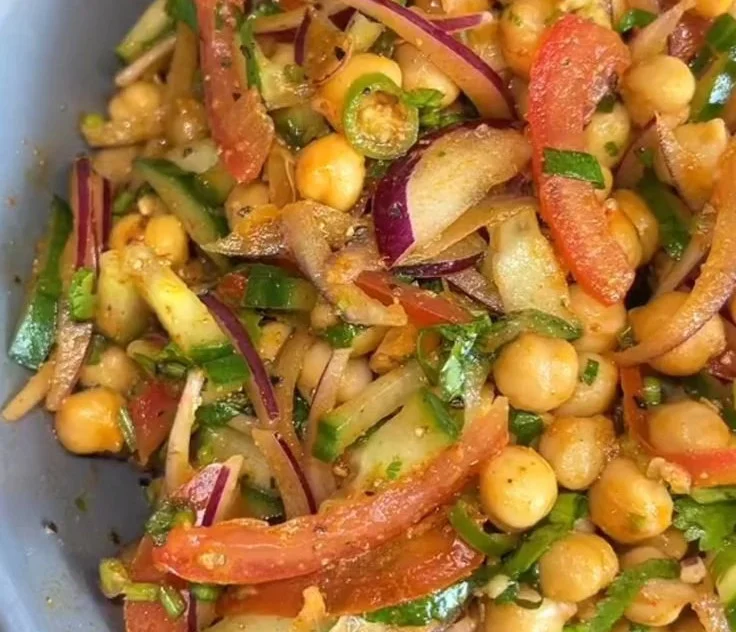 Colorful healthy chickpea salad with fresh vegetables and dressing in a bowl