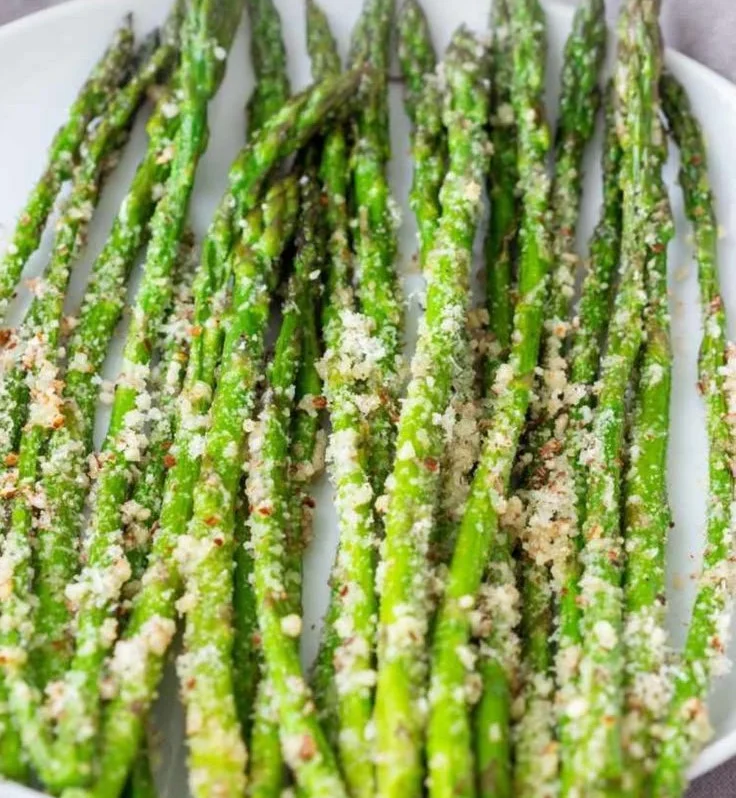 Delicious roasted asparagus with Parmesan cheese garnished on a plate.