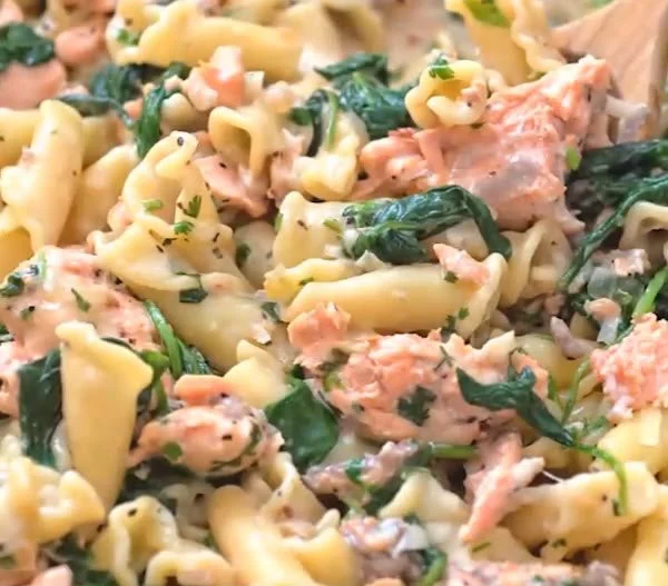 A bowl of creamy Salmon Pasta with Spinach garnished with parsley.