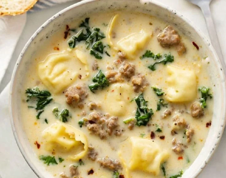 Bowl of Sausage Tortellini Soup with fresh herbs and toppings