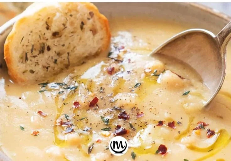 Delicious Vegan Garlic Chickpea Soup in a bowl garnished with herbs.