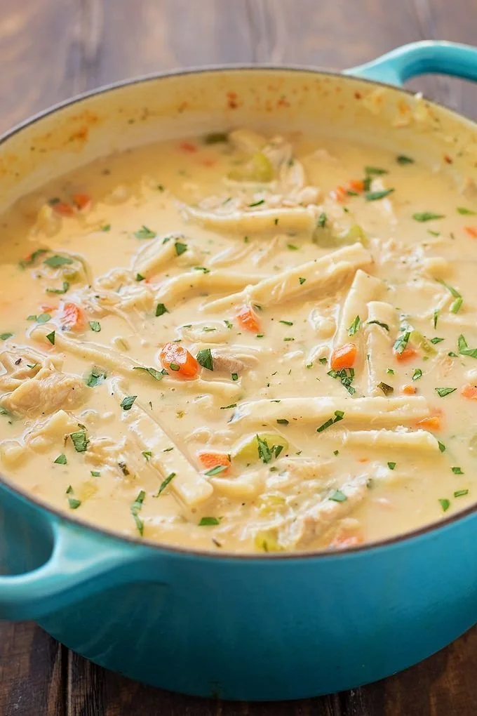 Creamy chicken noodle soup in a bowl with fresh herbs and vegetables