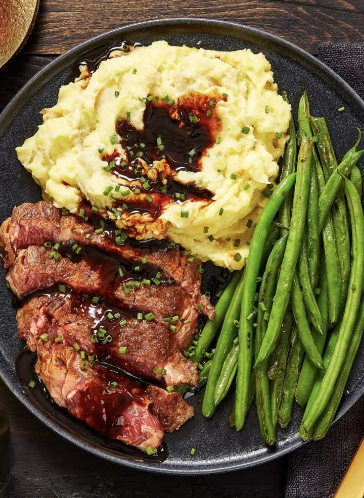 Gourmet steak served with mashed potatoes and green beans on a plate.