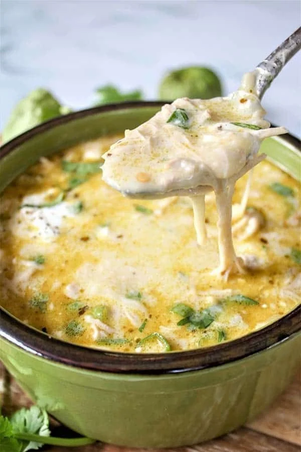 Creamy green chicken enchilada soup garnished with cheese and cilantro.