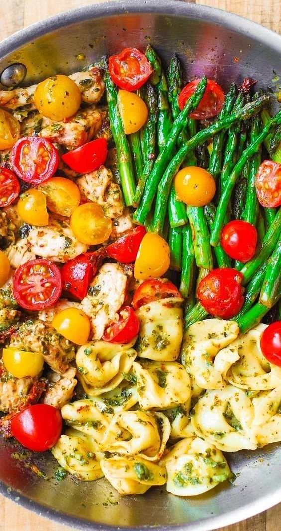 Plate of Basil Pesto Chicken with tortellini, asparagus, and cherry tomatoes.